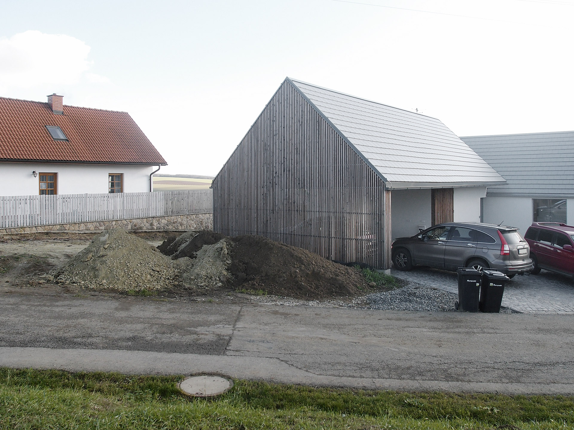 Kryté stání u domu, dřevěný štít do ulice